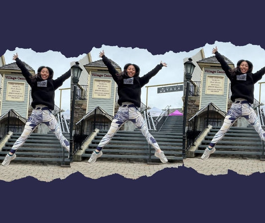 Angie joyfully jumping in the air wearing Umindak’s Cloud 9 'Worthy Telopea' leggings in front of a mountain village yoga studio — a celebration of self-expression, movement, and radiating positive energy.